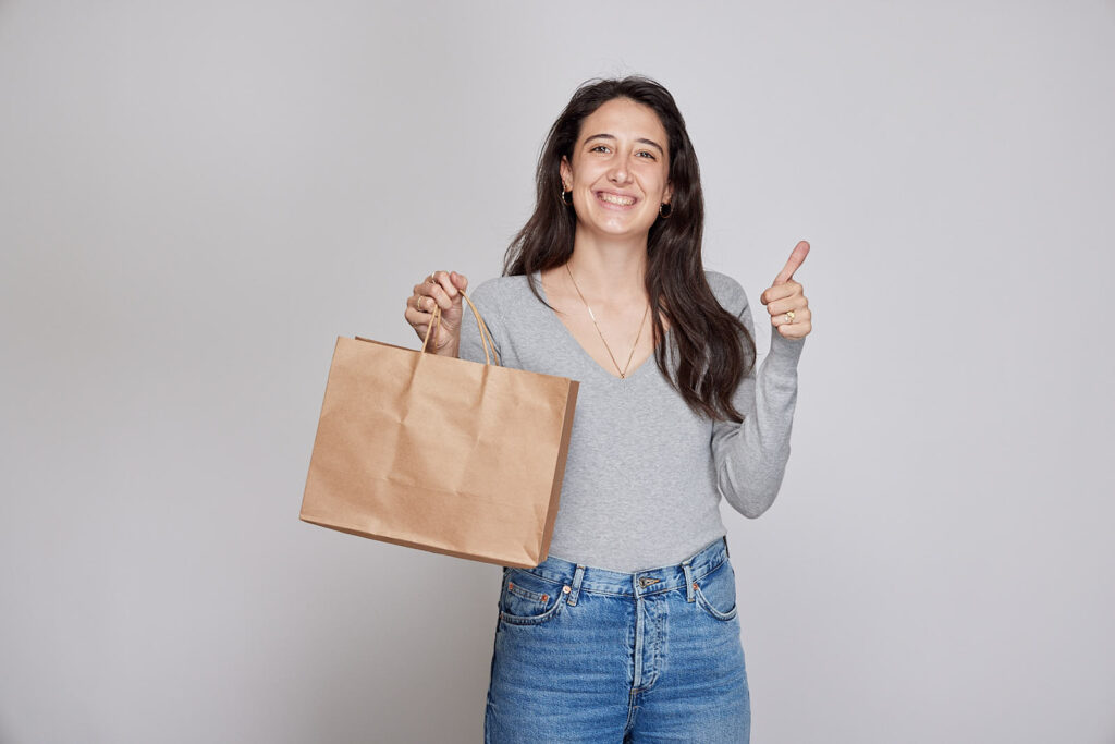 Types of customers and how to retain them - woman holds a paper bag shows thumbs up and smiles - borzo delivery